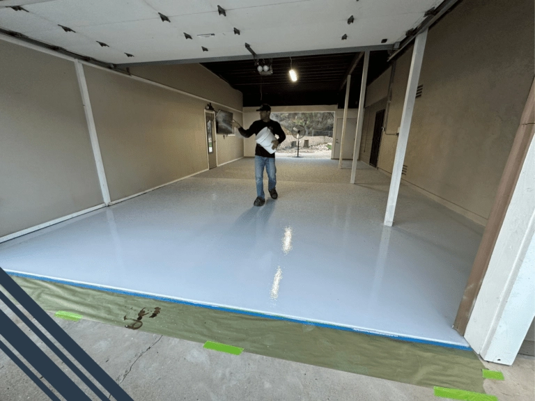 Man applying epoxy coating to a freshly prepared garage floor, showcasing the installation process for durable flooring solutions in San Diego.
