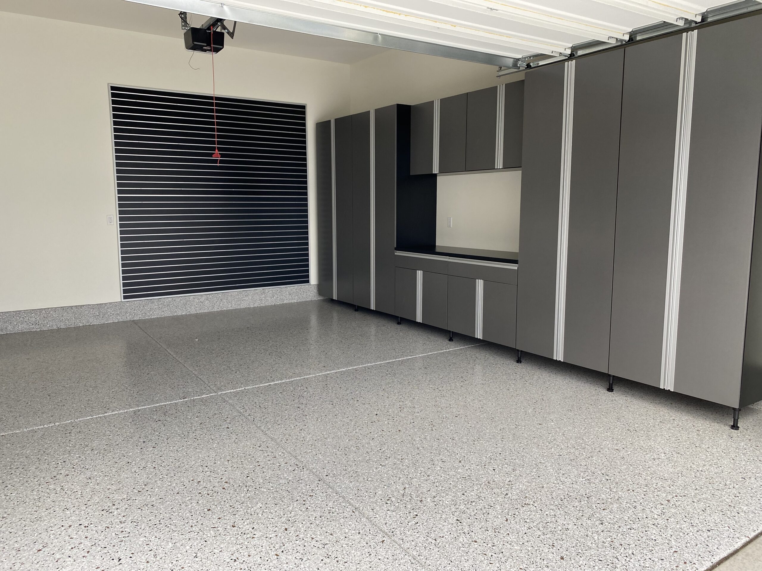 Modern garage interior featuring sleek gray cabinetry, polished epoxy flooring, and a contemporary wall design, emphasizing stylish and functional garage transformations in San Diego.