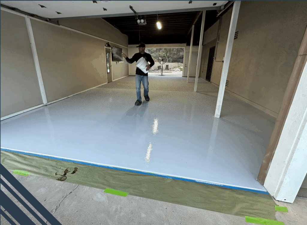 Man applying epoxy coating to a freshly prepared concrete floor in a garage, showcasing a durable and seamless finish ideal for high-traffic areas.