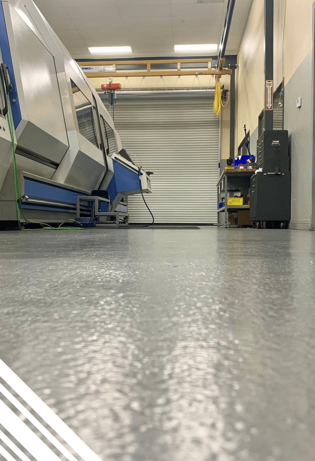 Industrial epoxy flooring in a workspace featuring machinery, showcasing durability and cleanliness essential for Pristine Epoxy's flooring solutions.