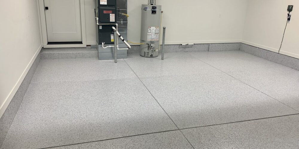Epoxy flooring installation in a clean, well-lit garage featuring a seamless, non-porous surface, promoting hygiene and durability for commercial spaces.