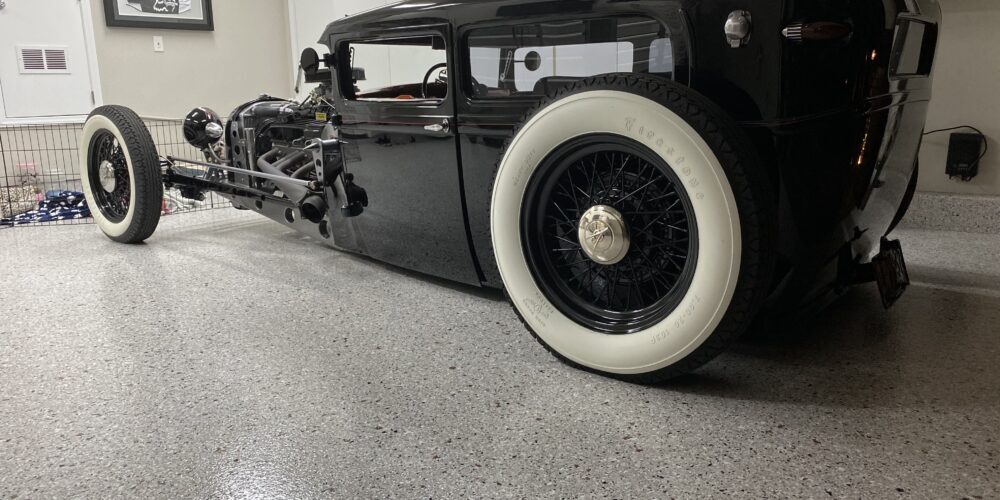 Classic hot rod parked on a stylish epoxy garage floor, showcasing durable and easy-to-maintain surface with a smooth, glossy finish.