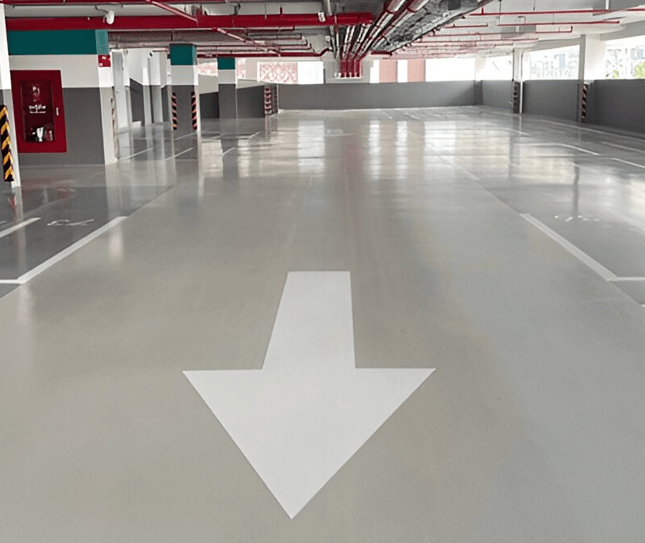 Epoxy-coated parking garage floor with clear directional arrow, showcasing clean and polished surface ideal for commercial and residential spaces.